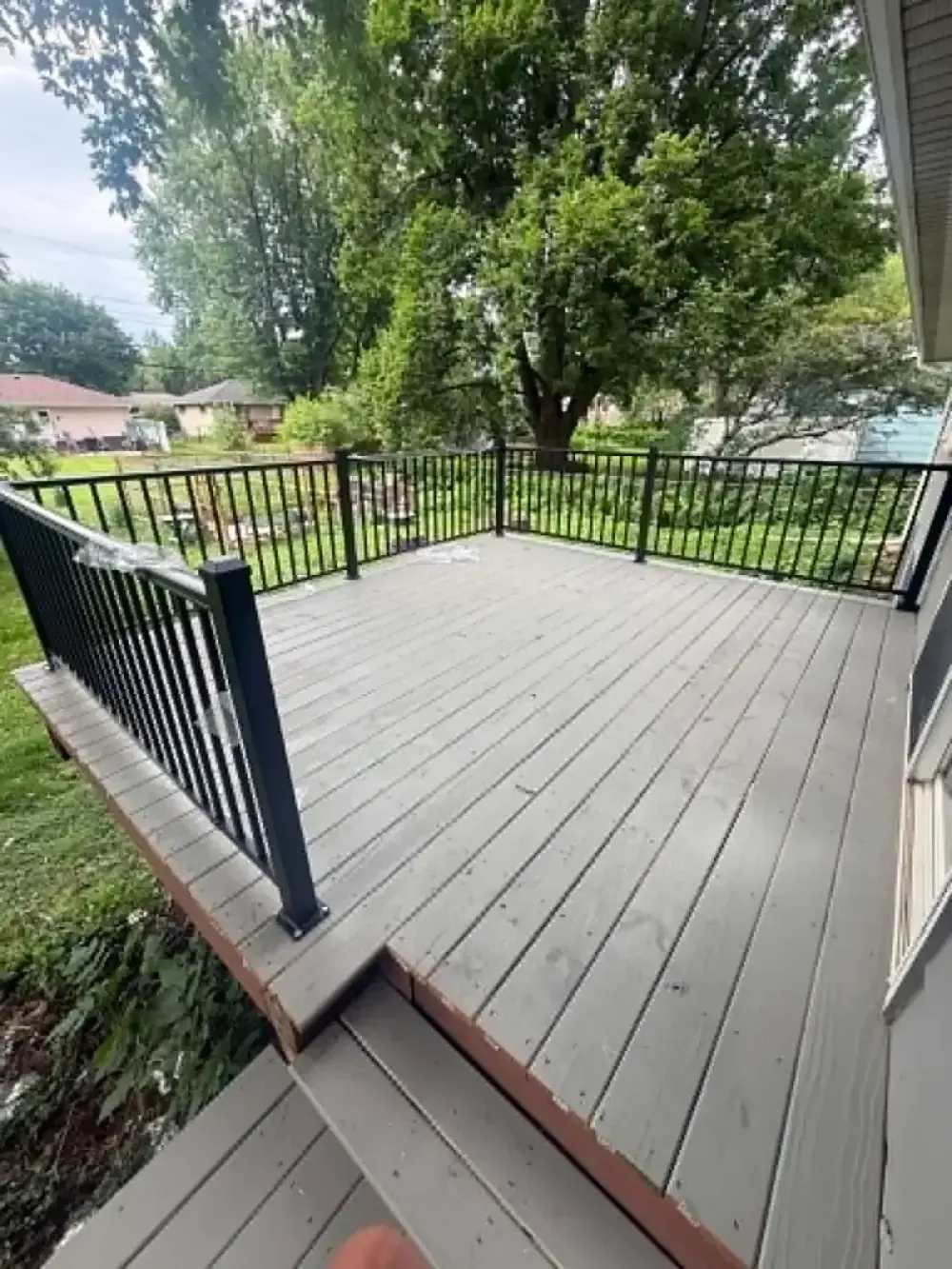 New gray composite deck with black aluminum railing built off the back of a house